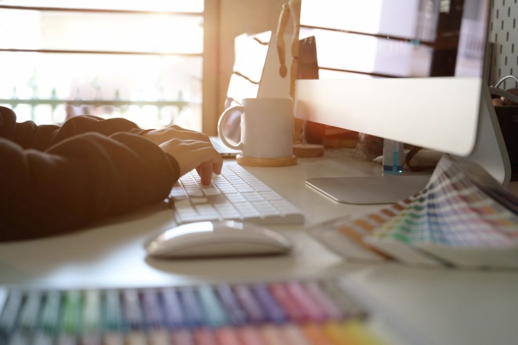 Designer working at a computer beside colour swatches