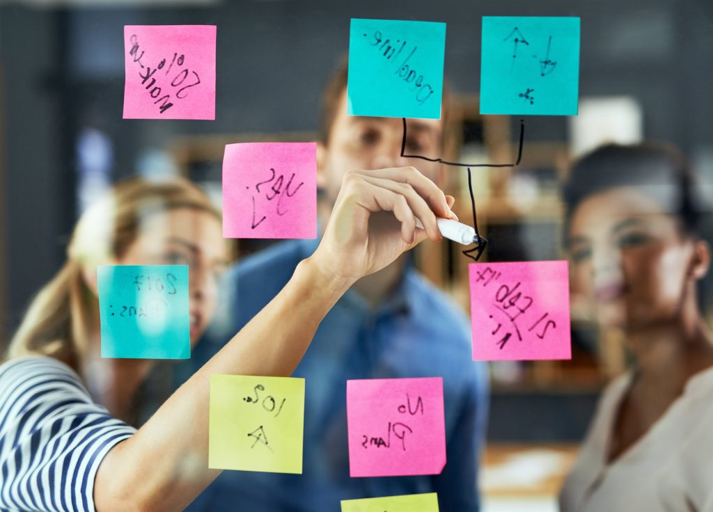 Team planning a project with notes on a glass board